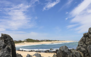 Rocks on beach with logo in the corner bottom right