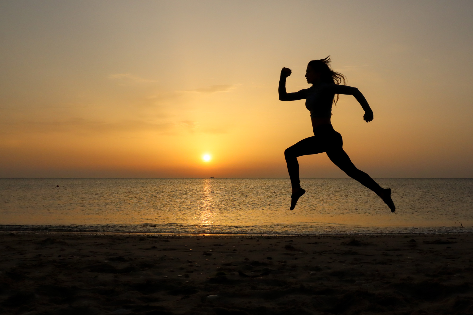 woman alone at dawn on beach with sunrise running